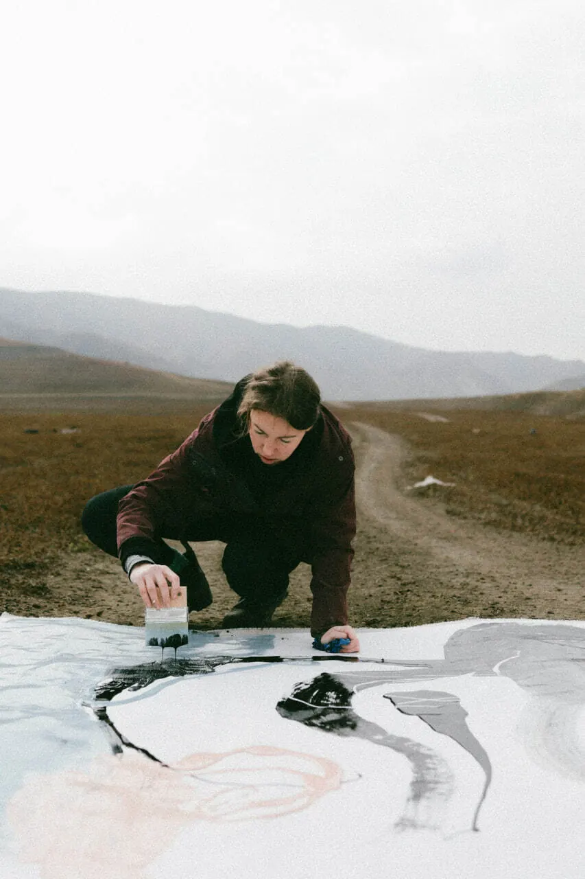 Working on a drawing laid directly on the ground