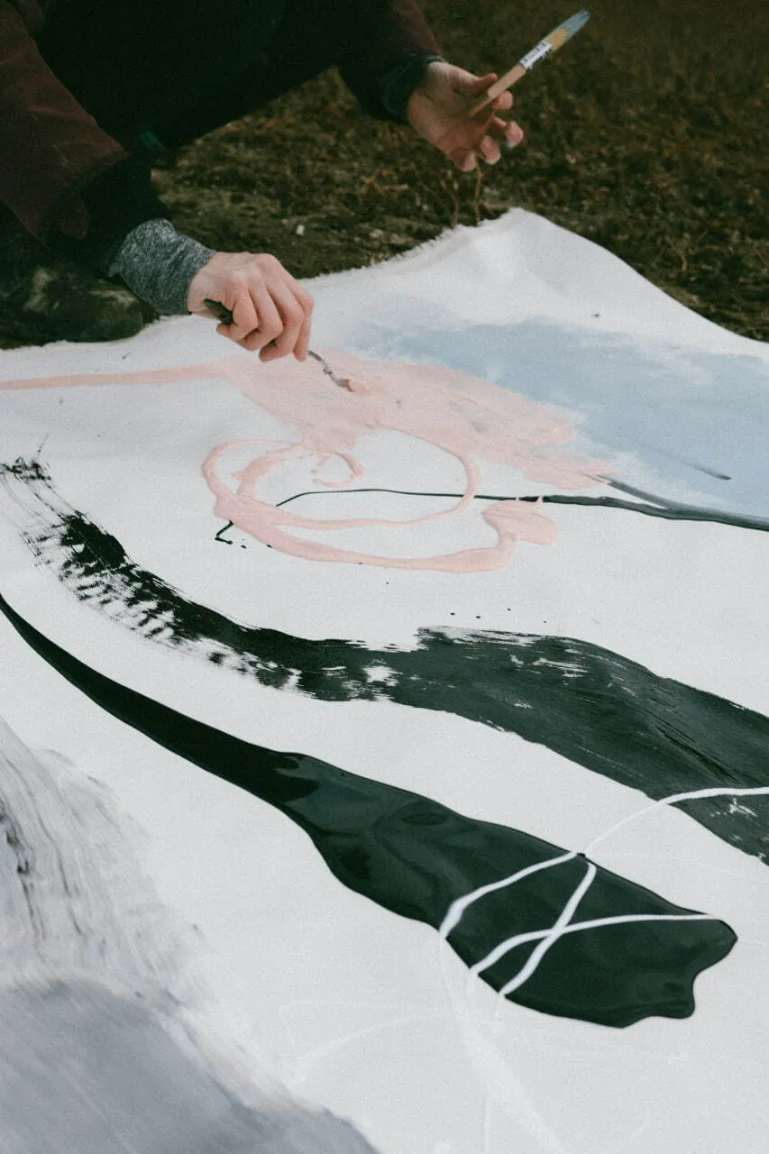 Hands painting a large sheet outdoors